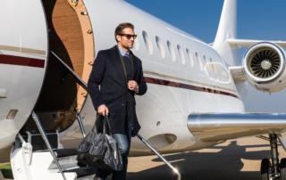 A man dressed in a-suit-disembarking-from-a-private-jet